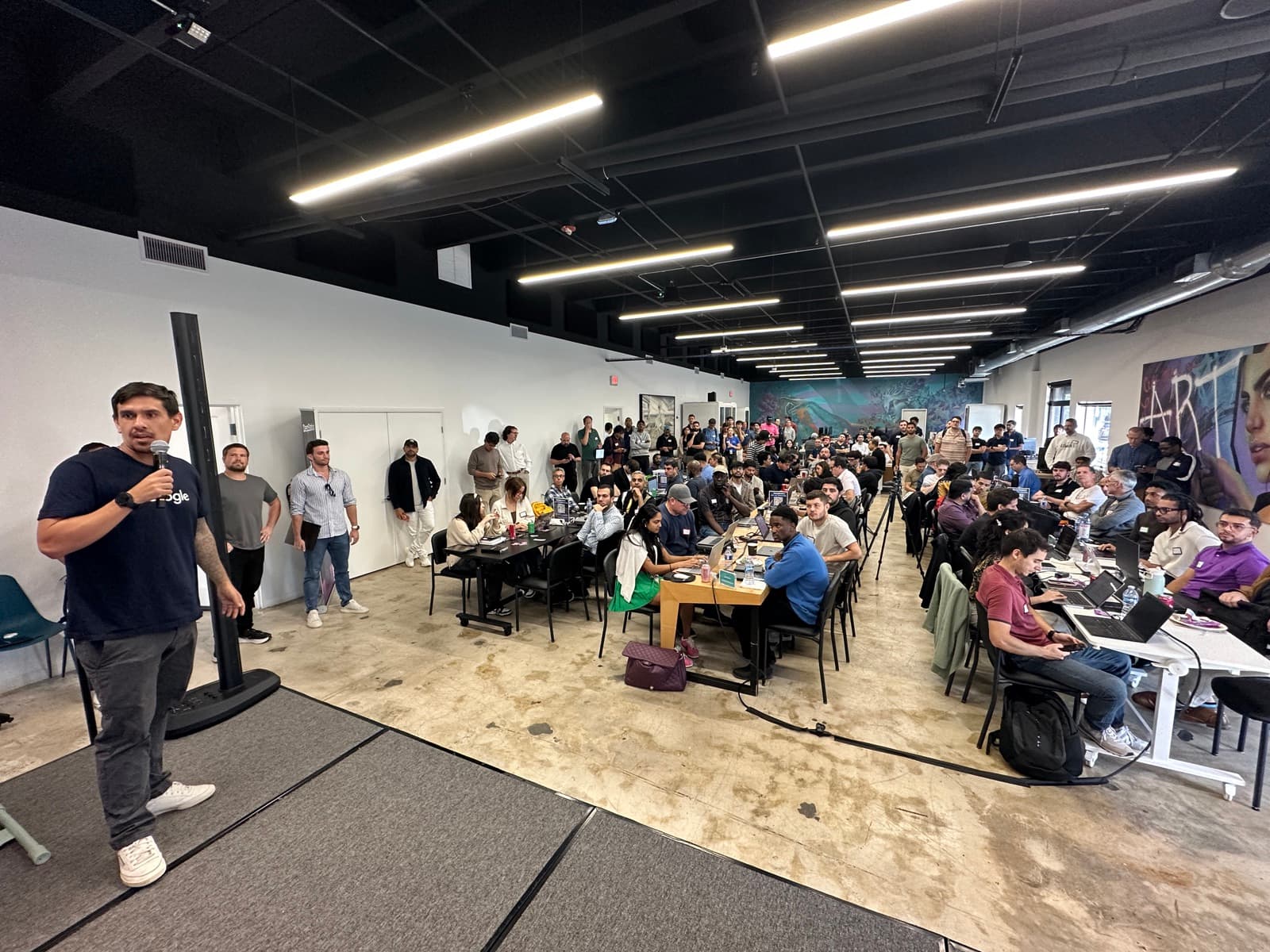 Presenter on stage with crowd at the Google Hackathon