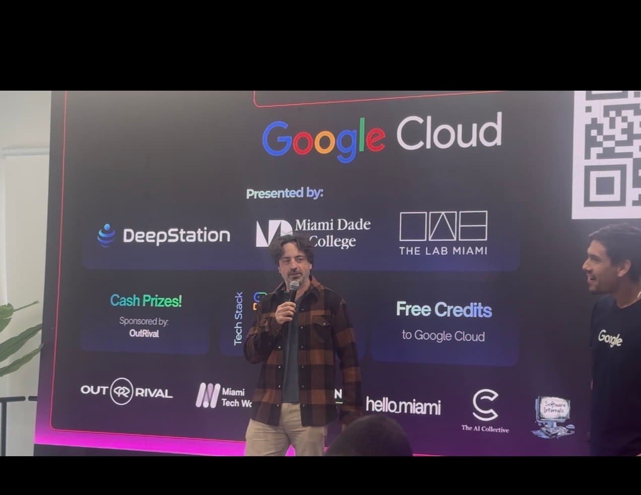 Sergey Brin speaking on stage with DeepStation logo behind him