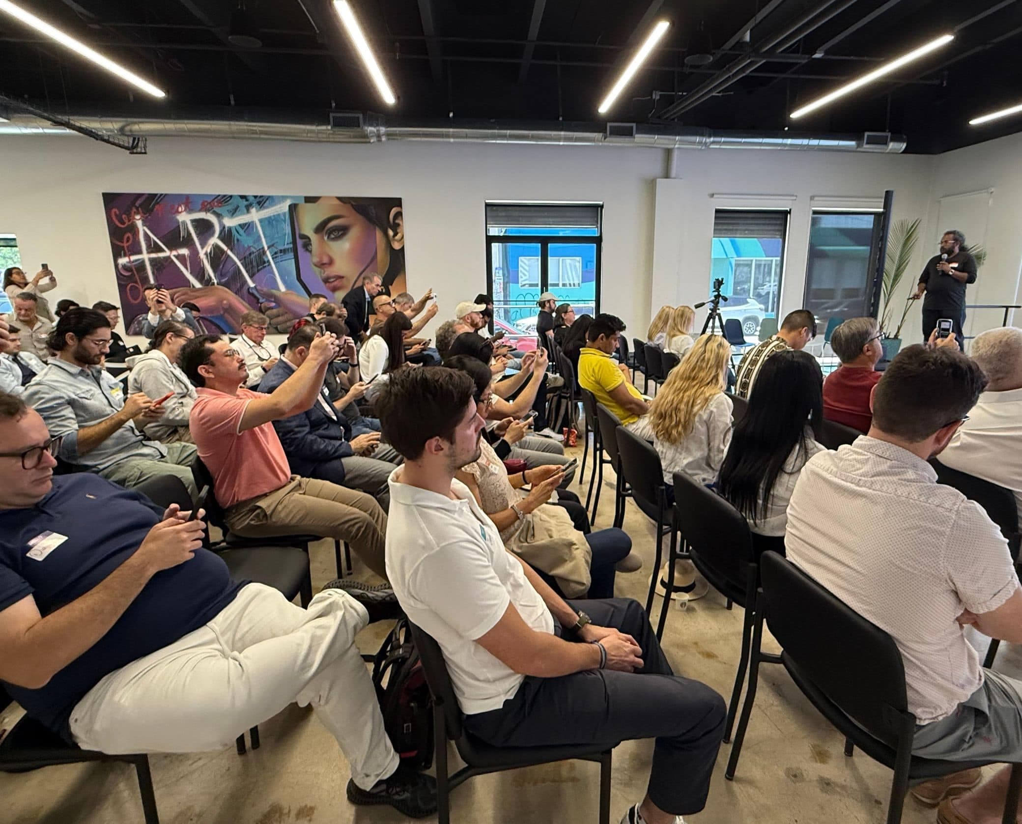 Summit attendees hold up their phones to capture a talk